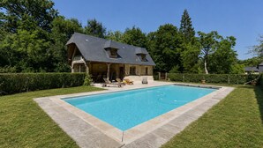 A house with a swimming pool, surrounded by a well-maintained lawn and trees. - La Bécassière | Family Normandy house with pool & nature (Genneville)