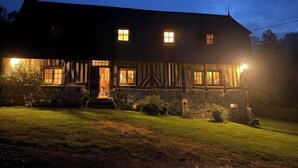 A traditional building with a symmetrical facade, multiple windows, and a well-lit entrance. - La Bécassière | Family Normandy house with pool & nature (Genneville)