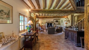 A rustic interior with exposed wooden beams, a fireplace, a dining area, and a kitchen. - La Bécassière | Family Normandy house with pool & nature (Genneville)