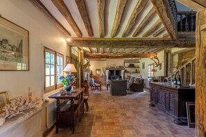 Un interior rústico con vigas de madera a la vista, una chimenea, un comedor y una cocina.