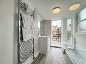 Et moderne badeværelse med bruser, vask og spejl. Der er udsigt til det fri gennem et vindue.
