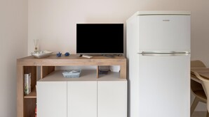 A kitchenette with a white refrigerator, a wooden countertop, a black TV, and a small blue decorative item. - Apartment With sea View Terrace and air Conditioning (Castelsardo)