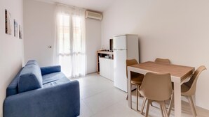 A compact living space with a kitchenette, a dining area, and a sofa. - Apartment With sea View Terrace and air Conditioning (Castelsardo)