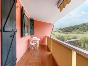 A balcony with a table and chairs, a closed door, and a view of a hilly landscape. - Apartment With sea View Terrace and air Conditioning (Castelsardo)
