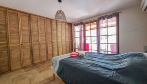 Une chambre à coucher avec un lit, une armoire en bois et une fenêtre avec des rideaux.