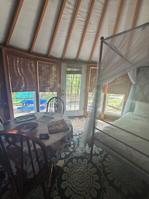 A tent with a bed, a table with a basket, and a chair.