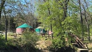 Un terrain de camping au bord de la rivière, équipé de tentes et de tables de pique-nique.