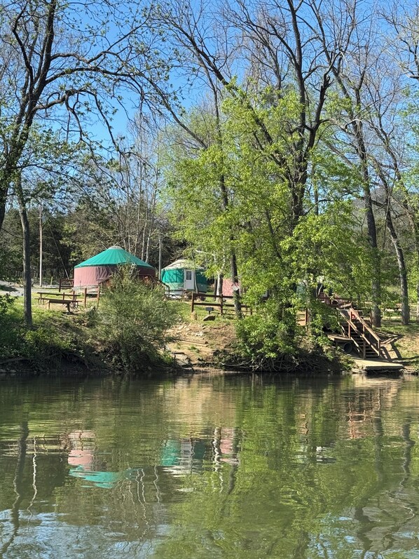 A riverside campsite with tents and picnic tables.
