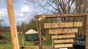 Une enseigne en bois portant les inscriptions « ROCK TAVERN » et « RIVER KAMP », ainsi qu’un numéro de téléphone.