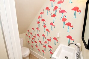 A bathroom with a toilet, sink, and a wall with a pattern of red flamingos. - Miami Havana Nights -Parking, Close to Brickell, LoanDepot (Miami)
