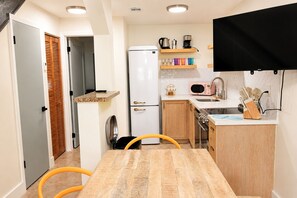A compact kitchen with a refrigerator, microwave, and stove, wooden cabinets, and a small countertop. - Miami Havana Nights -Parking, Close to Brickell, LoanDepot (Miami)