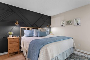 Ein Schlafzimmer mit Bett, Nachttischen, einer Kommode und Wandbildern.