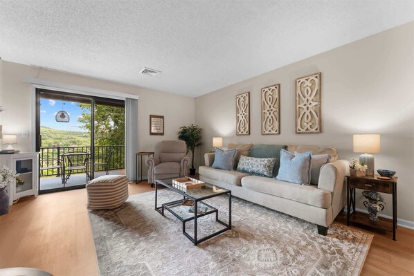 A living room with a sofa, armchairs, a coffee table, a patterned rug, and decorative wall art. - The View on Overlook Balcony (Branson)