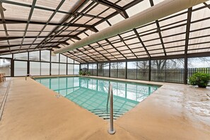 An indoor swimming pool with a glass ceiling, clear pool water, and a view of the outside. - The View on Overlook Balcony (Branson)