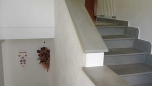 En trappe med hvid gelænder og trin, en lille dekorativ vase og en radiator på væggen.