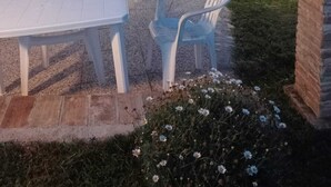 En udendørs terrasse med jacuzzi, hvide plastikstole og borde.