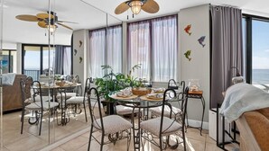 Une chambre d’hôtel avec balcon, un coin repas comprenant une table ronde et des chaises, et un ventilateur de plafond.