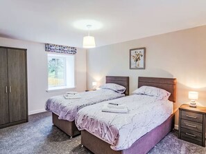 Ein Schlafzimmer mit zwei Betten, einem Kleiderschrank, einem Fenster mit Aussicht und einem Wandbild.