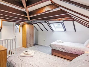 Une chambre avec un plafond en pente, un lit, une armoire et une fenêtre.