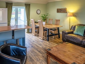 Ein gemütliches Wohnzimmer mit Essbereich, einer Couch, einem Couchtisch und einer Lampe.