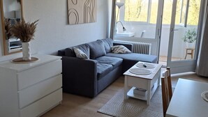 Ein modernes Wohnzimmer mit einer Couch, einem Couchtisch, einem Esstisch und einer weißen Kommode.