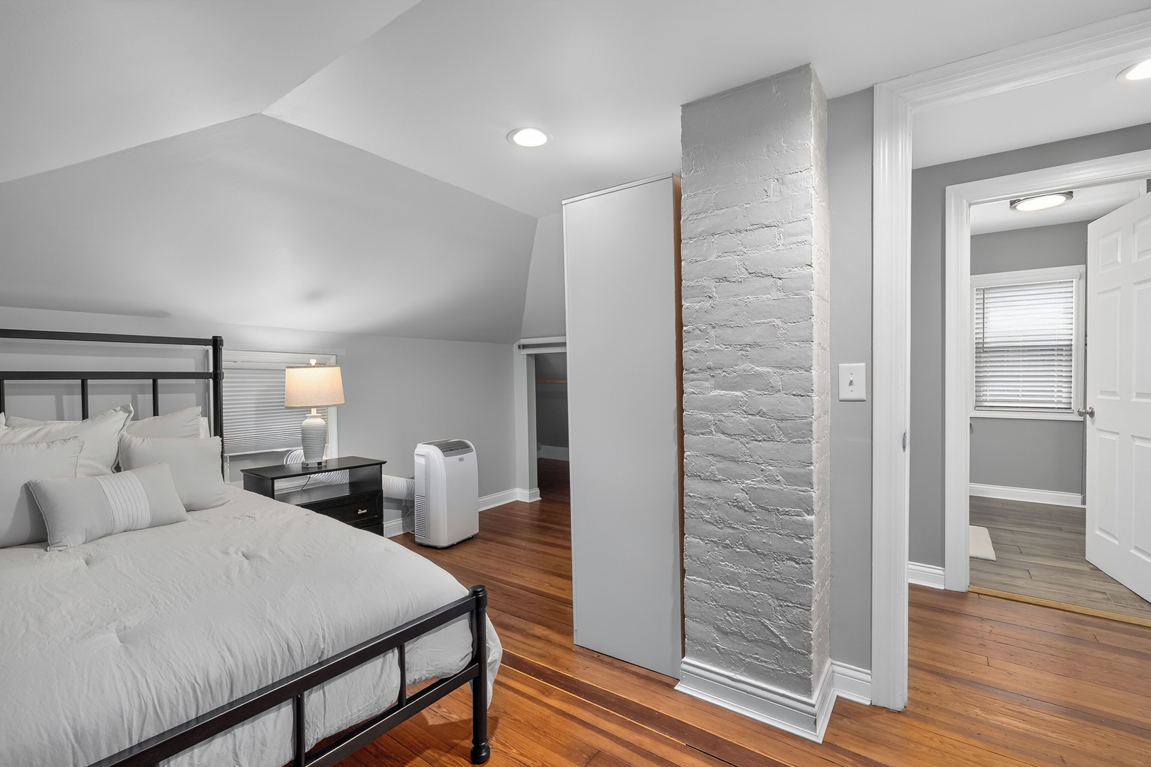 Une chambre à coucher comprenant un lit, une table de chevet, une lampe et un radiateur fixé au mur.