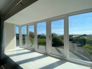 Ein Zimmer mit großen Fenstern, Blick auf eine ländliche Landschaft und einem Oberlicht.