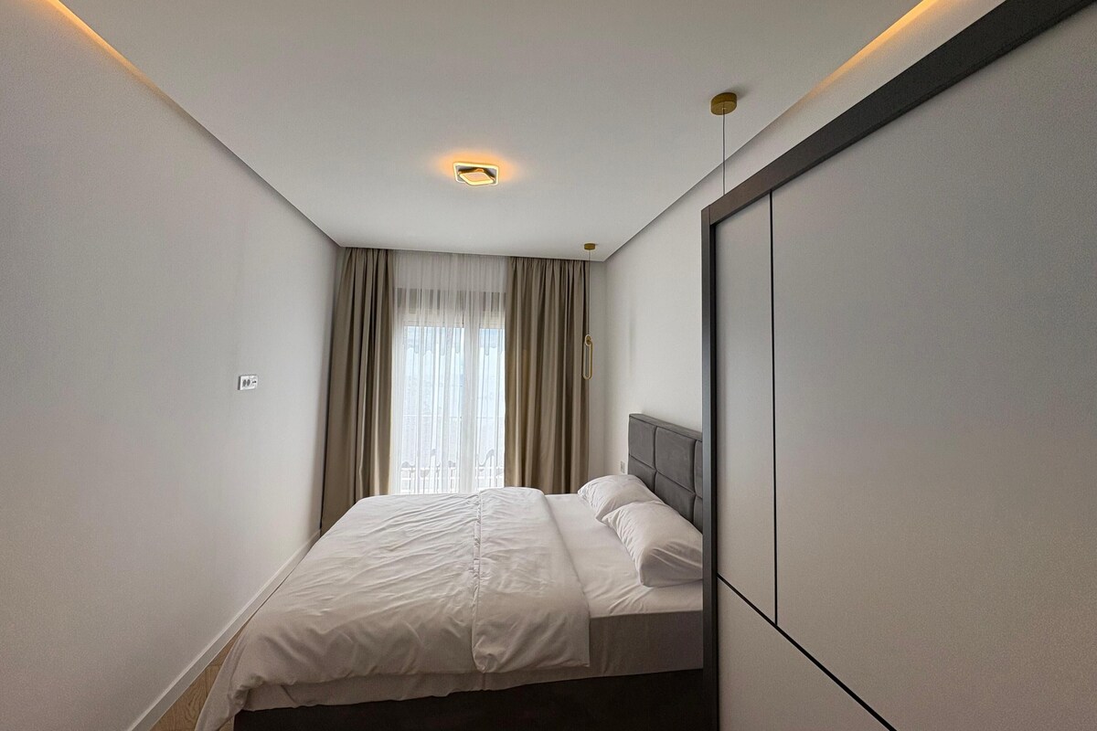 Une chambre d’hôtel moderne, équipée d’un lit, d’un grand miroir et d’un luminaire au plafond.