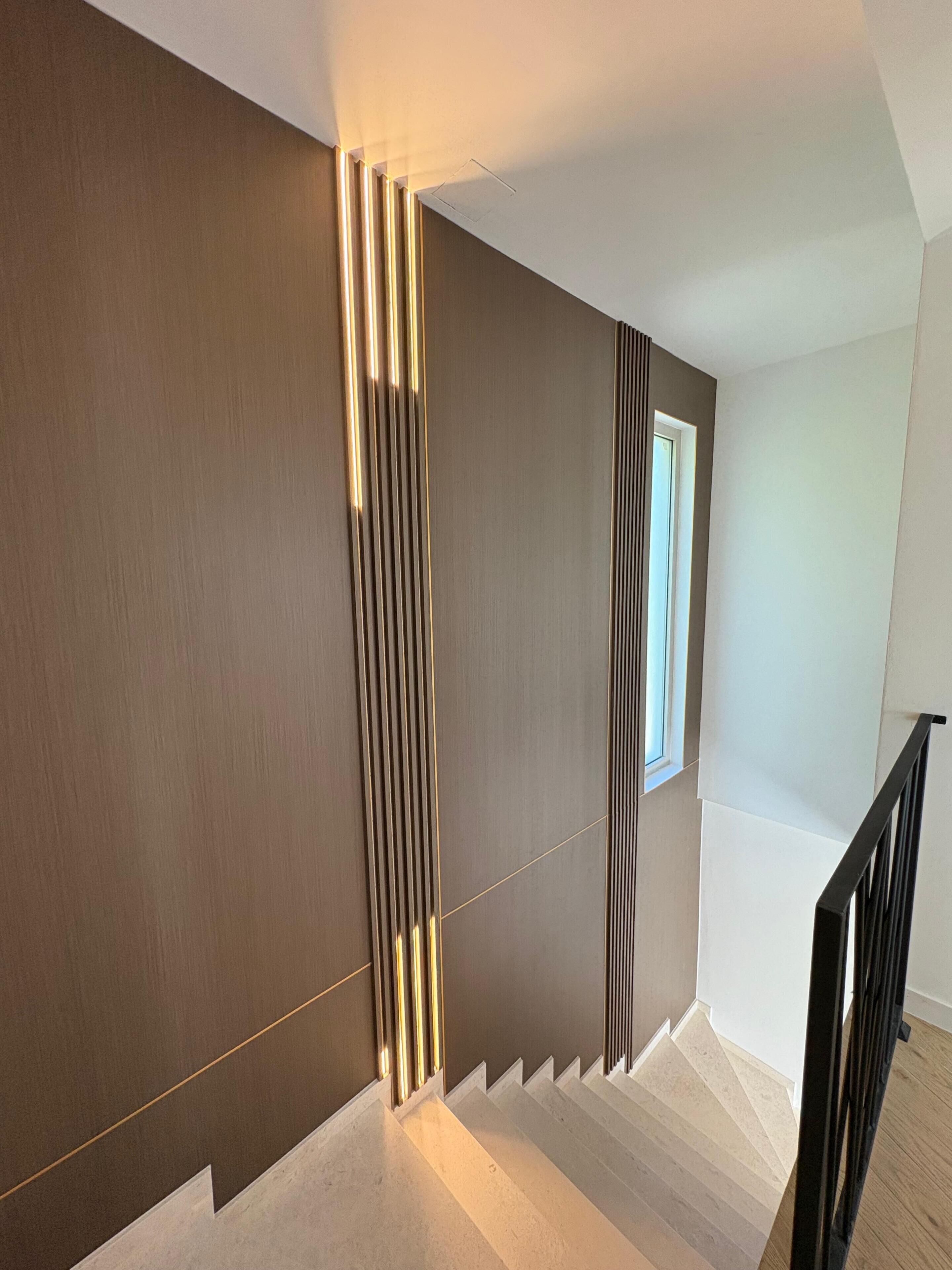 Ein modernes Interieur mit einer Treppe, einem Fenster und einer Wand mit vertikalen Linien.