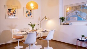 A dining area with a round table, white chairs, a map on the wall, and a pendant light. - Casa Macor (Venice)