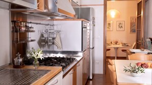 A modern kitchen with stainless steel appliances, wooden cabinets, and a dining area with a table and chairs. - Casa Macor (Venice)