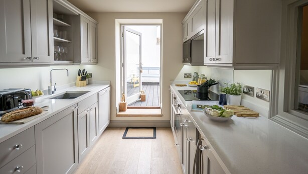 A modern kitchen with white cabinets, a built-in microwave, and a view to the outside. - The Cornstore -  a house that sleeps 6 guests  in 3 bedrooms (Southwold)