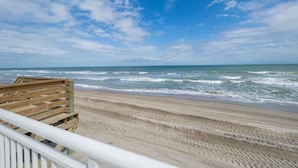Een strand met een houten bank en een leuning.
