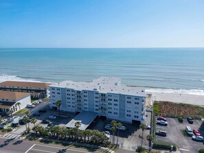 A multi-story hotel with a parking lot, adjacent to a beach. - Oceanfront Satellite Beach | Modern & Updated (Satellite Beach)