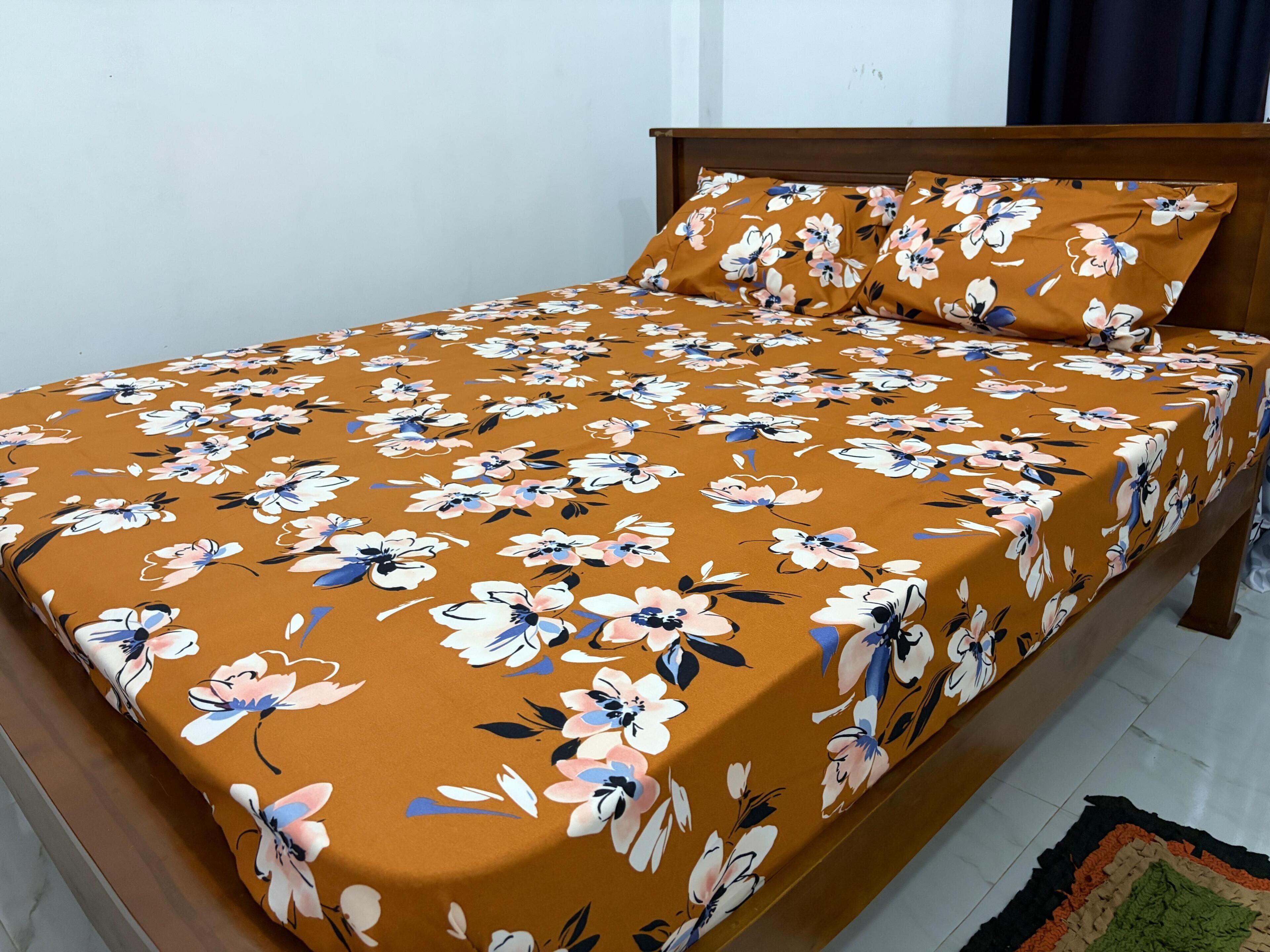 A bed with a floral bedspread and matching pillow, a wooden headboard, and a tiled floor.