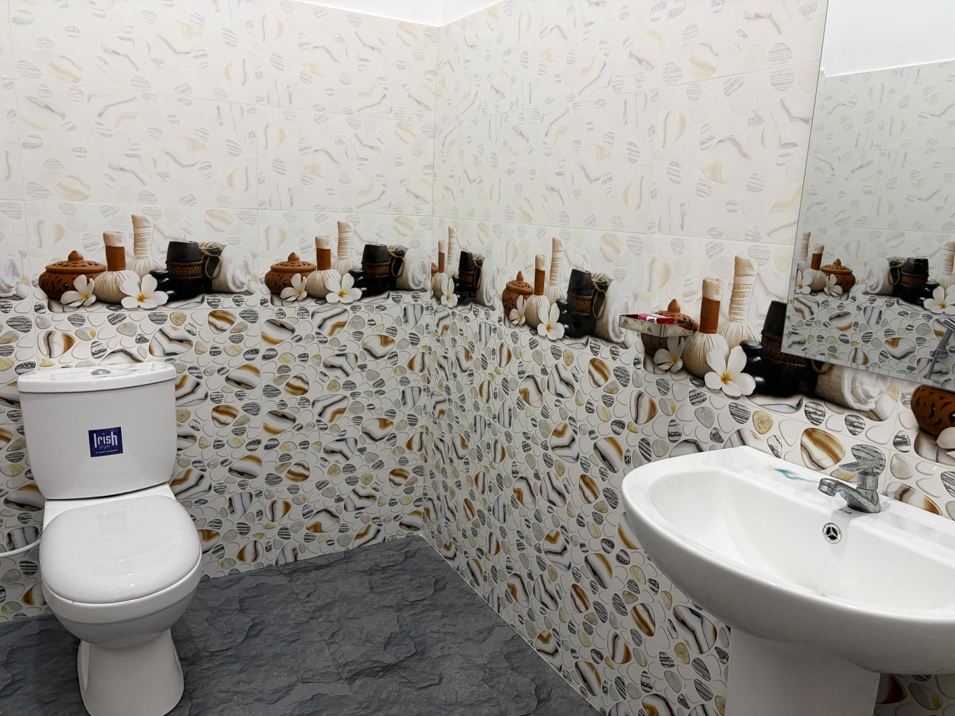A bathroom with a toilet, sink, and decorative wall tiles.