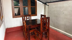 Una mesa de comedor de madera con sillas, una ventana con cortinas y un suelo rojo.