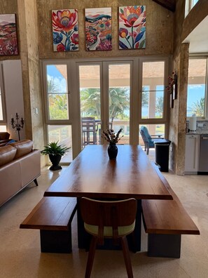 A spacious dining area with a wooden table, benches, and a view of the outdoors. - Beachfront, Luxury Oasis with Private Resort Pool (Palmer)