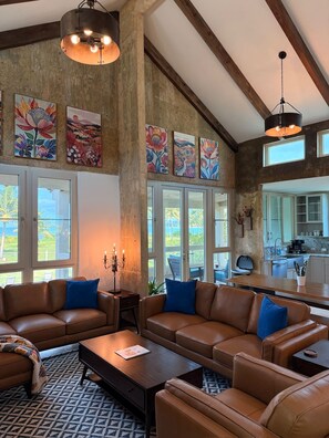 A spacious living area with leather sofas, a coffee table, and artwork on the walls. - Beachfront, Luxury Oasis with Private Resort Pool (Palmer)