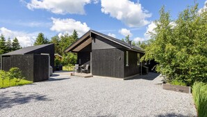 En modern byggnad med ett sluttande tak, en täckt uteplats och en grusuppfart.