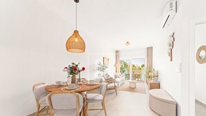 A modern dining area with a round table, chairs, and hanging pendant lights. - Marina Garden Swim-Up Suite, direct pool access, colourful boho chic resort retreat - by OYOOSTAYS (Pilar de la Horadada)