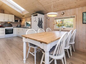 A modern kitchen with white cabinets, a wooden dining table, and white chairs. - 4 Star Holiday Home in Lokken (Lokken)