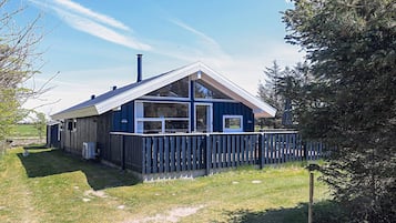 A blue house with a fenced yard and a chimney.