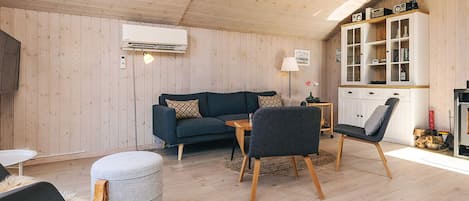 A cozy living room with a sofa, chairs, a coffee table, and a cabinet with shelves.
