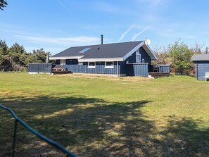 A single-story house with a sloped roof, a chimney, and a fenced yard. - 4 Star Holiday Home in Lokken (Lokken)