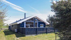 A blue house with a fenced yard, a chimney, and a large window. - 4 Star Holiday Home in Lokken (Lokken)