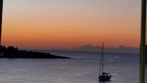A room with a large window overlooking a calm sea at sunset. - Cozy 1-bedroom apartment in front of the sea (Palermo)