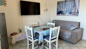 A dining area with a table, chairs, a television, and a sofa. - Cozy 1-bedroom apartment in front of the sea (Palermo)