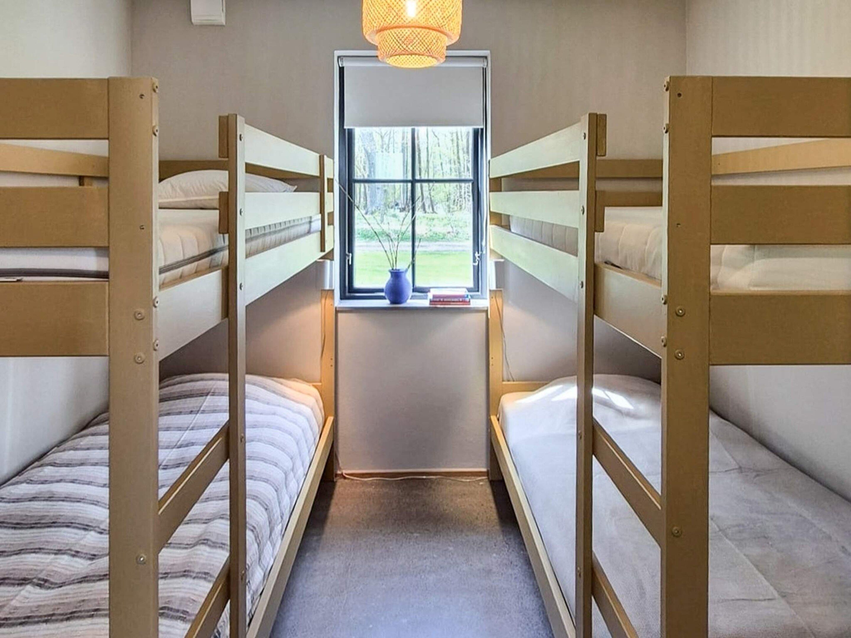 Habitación con literas, ventana y lámpara colgante.
