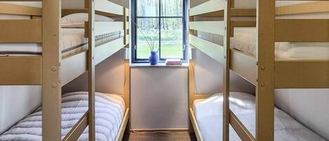 A bunk bed room with a window and a hanging light fixture.